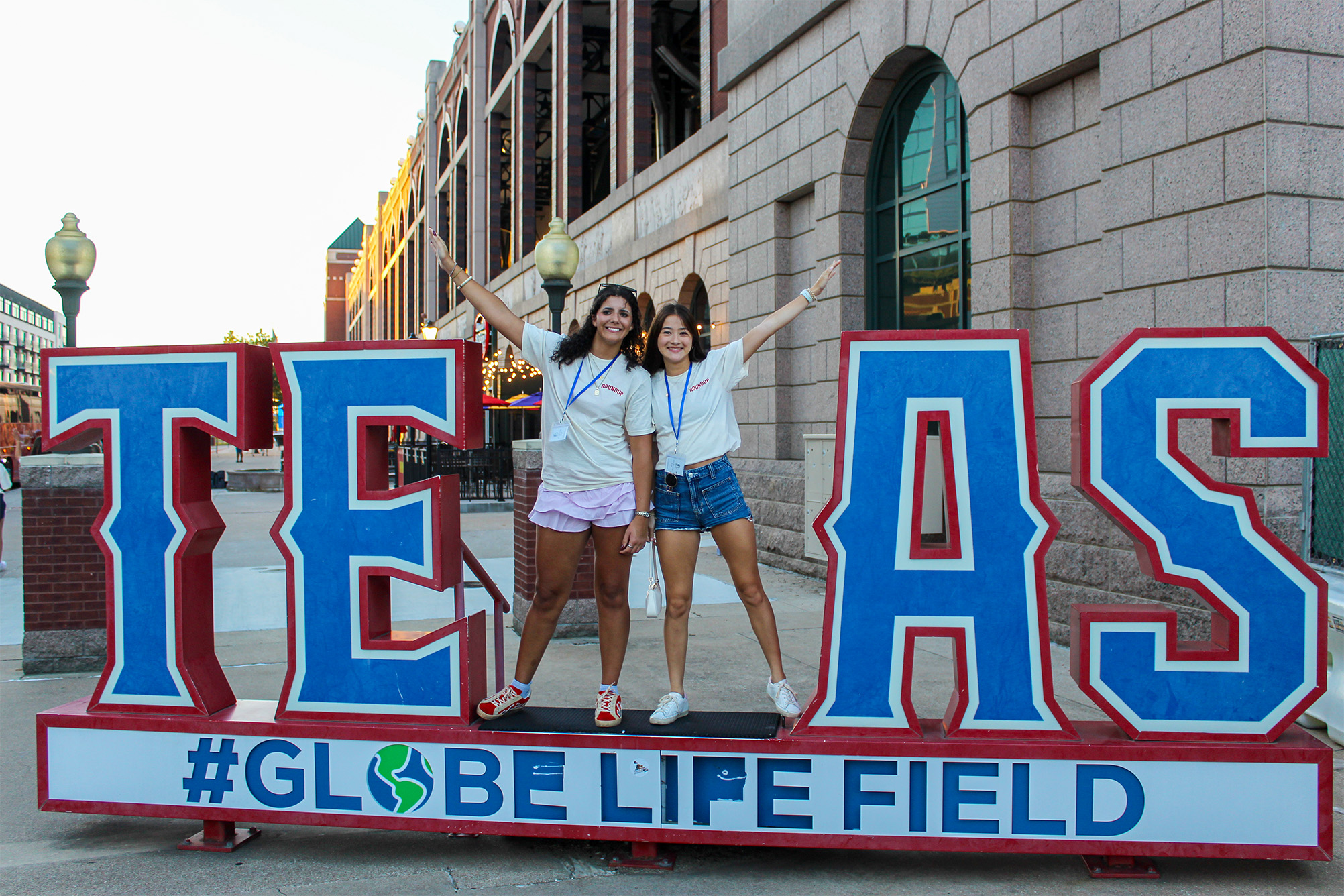 two people posing for photo in front of globe life stadium