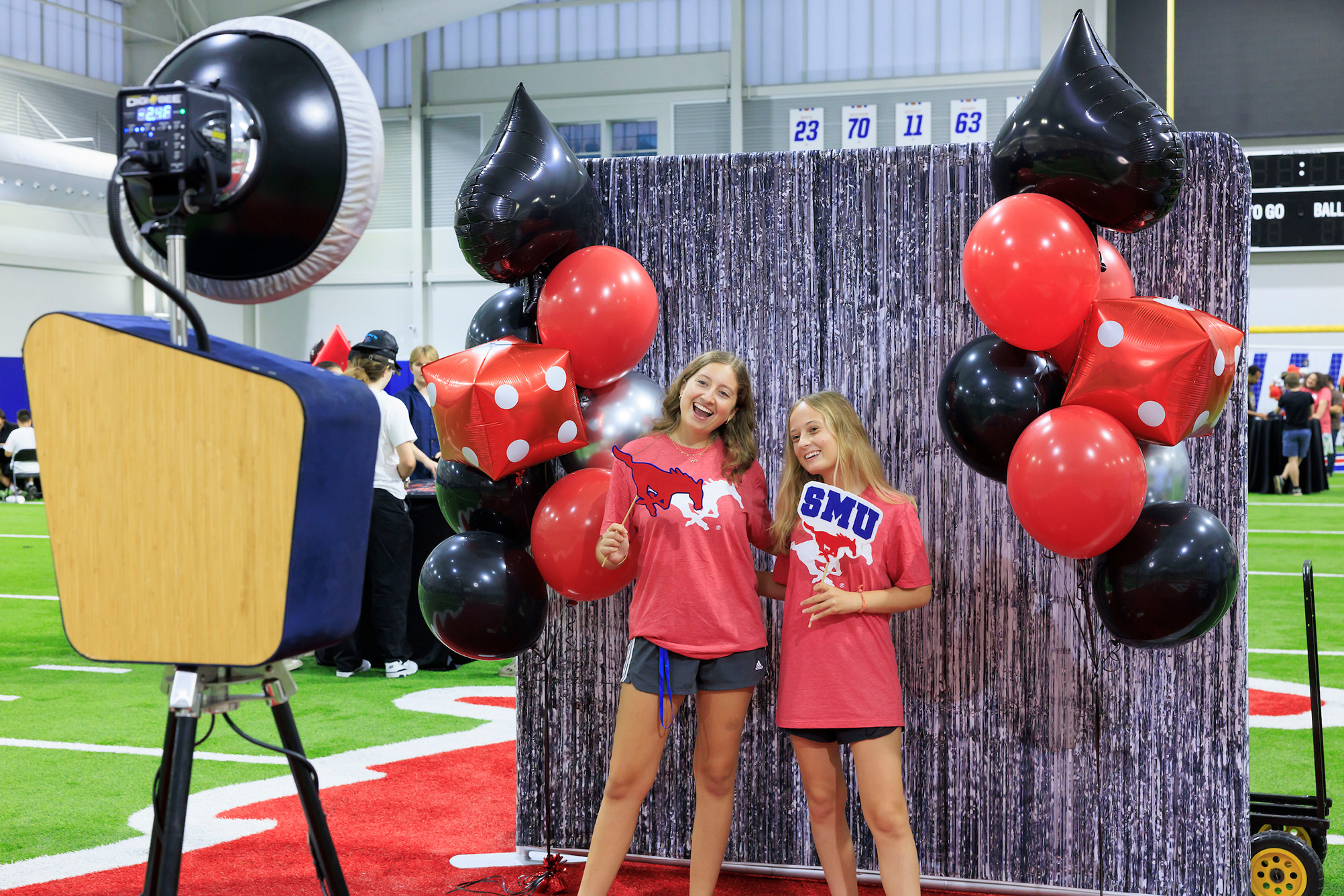 two students in red shirts in front of shiny backdrop posing for photo