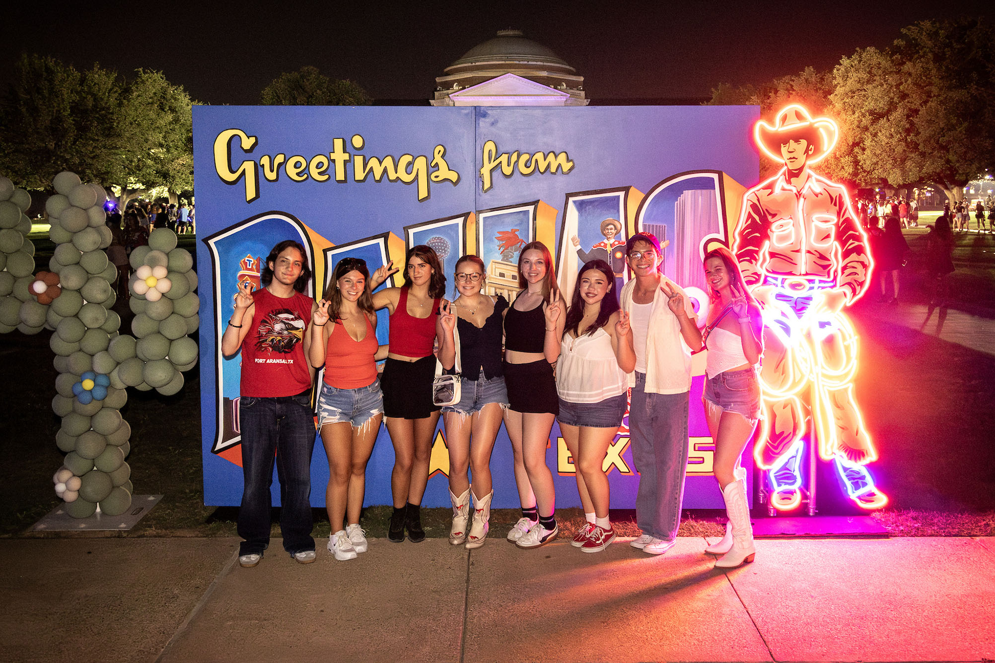 group of people standing in front of blue backdrop outside at night posing for a photo
