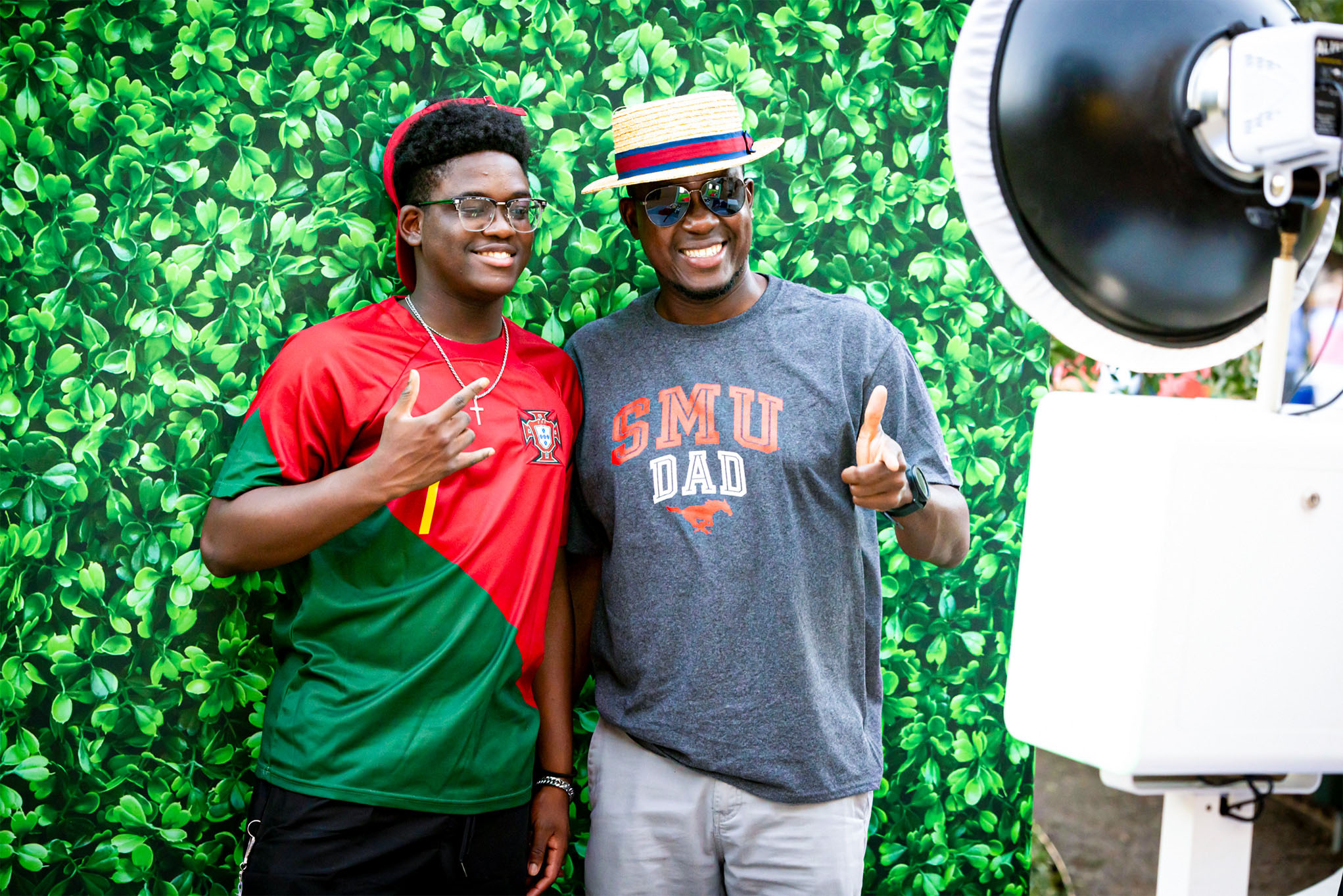 SMU Dad and Student taking photo in front of greenery wall during Family Weekend 2023