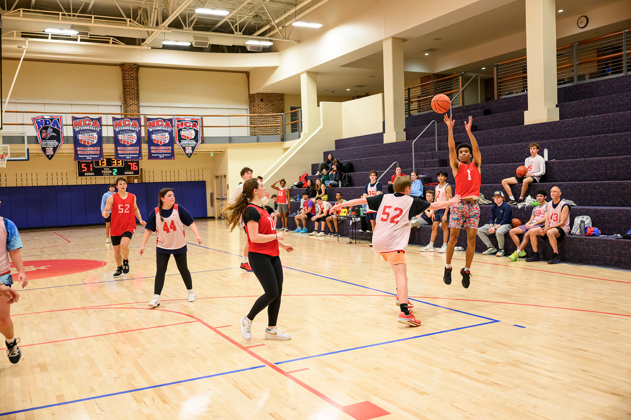 group of students playing indoor basketball with white and red jerseys
