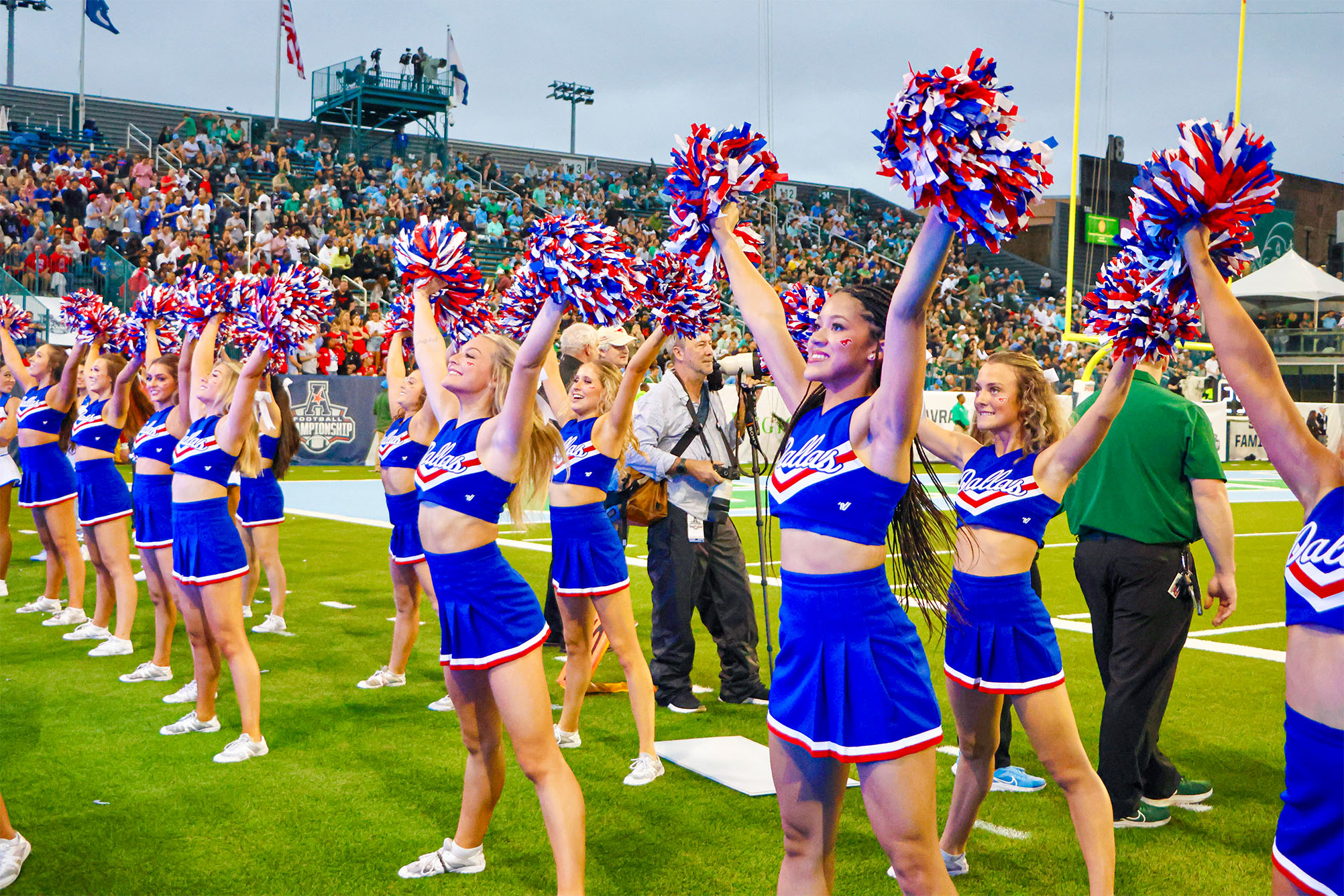 SMU cheerleaders at football game in blue uniforms with red, blue, and sliver pompoms