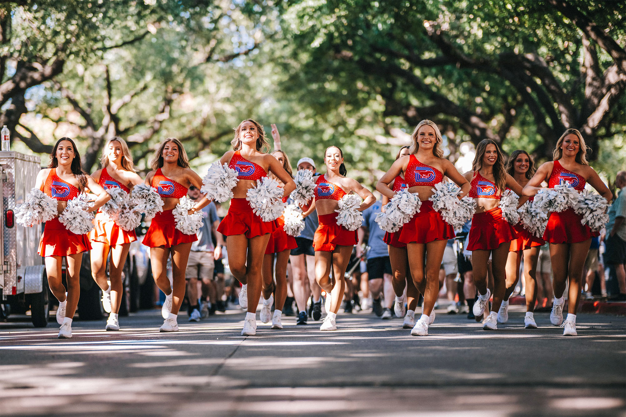 SMU pom and cheer walking down boulevard before football game in red triple D logo uniform