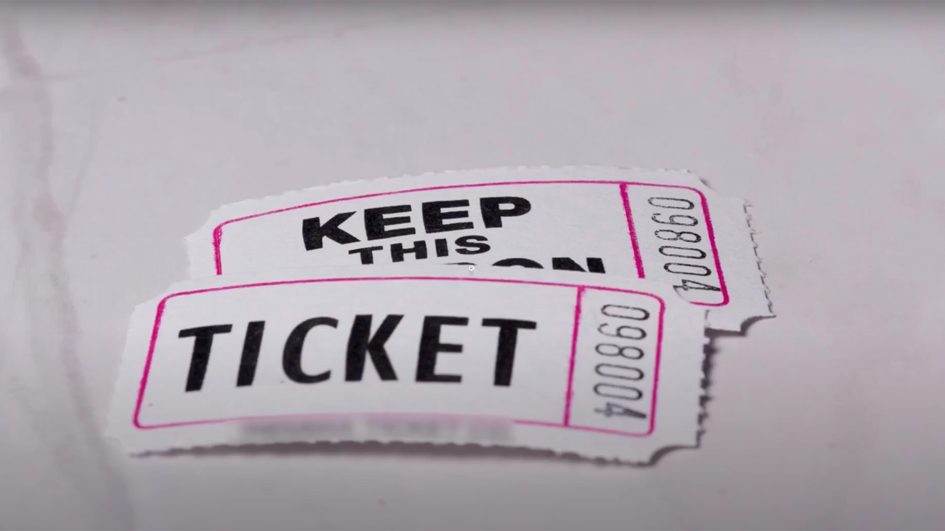 image of two white ticket stubs with pink outline and bold black lettering