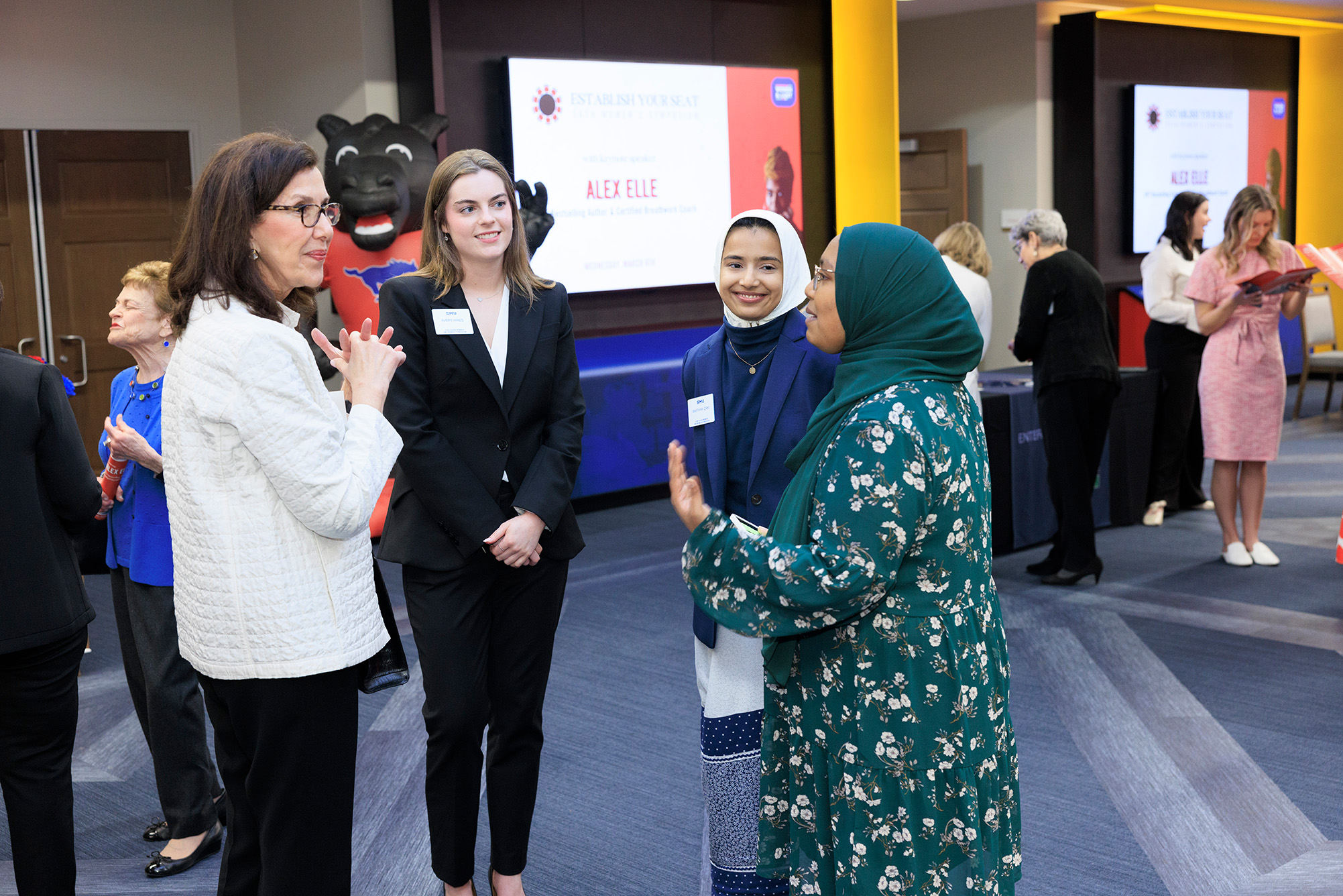 four people standing inside talking in open meeting space