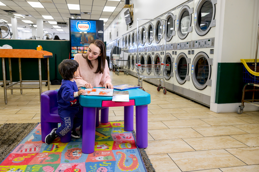 In the Scrub-a-Dubs laundromat in East Dallas, Ryland Adzich reads a book to three-year-old Noah from the library she created there.