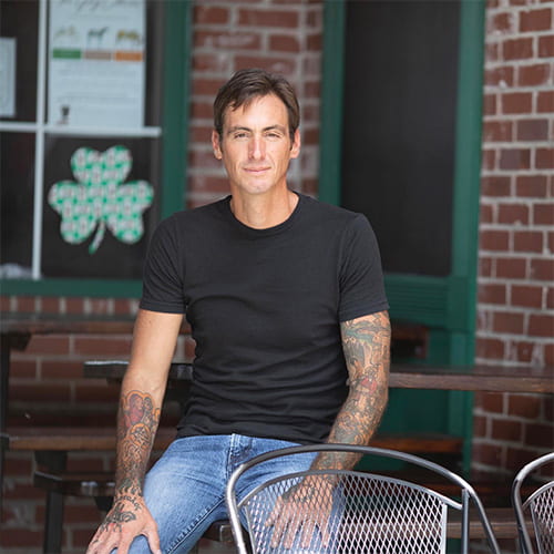 Michael Beck in casual attire leaning on a table
