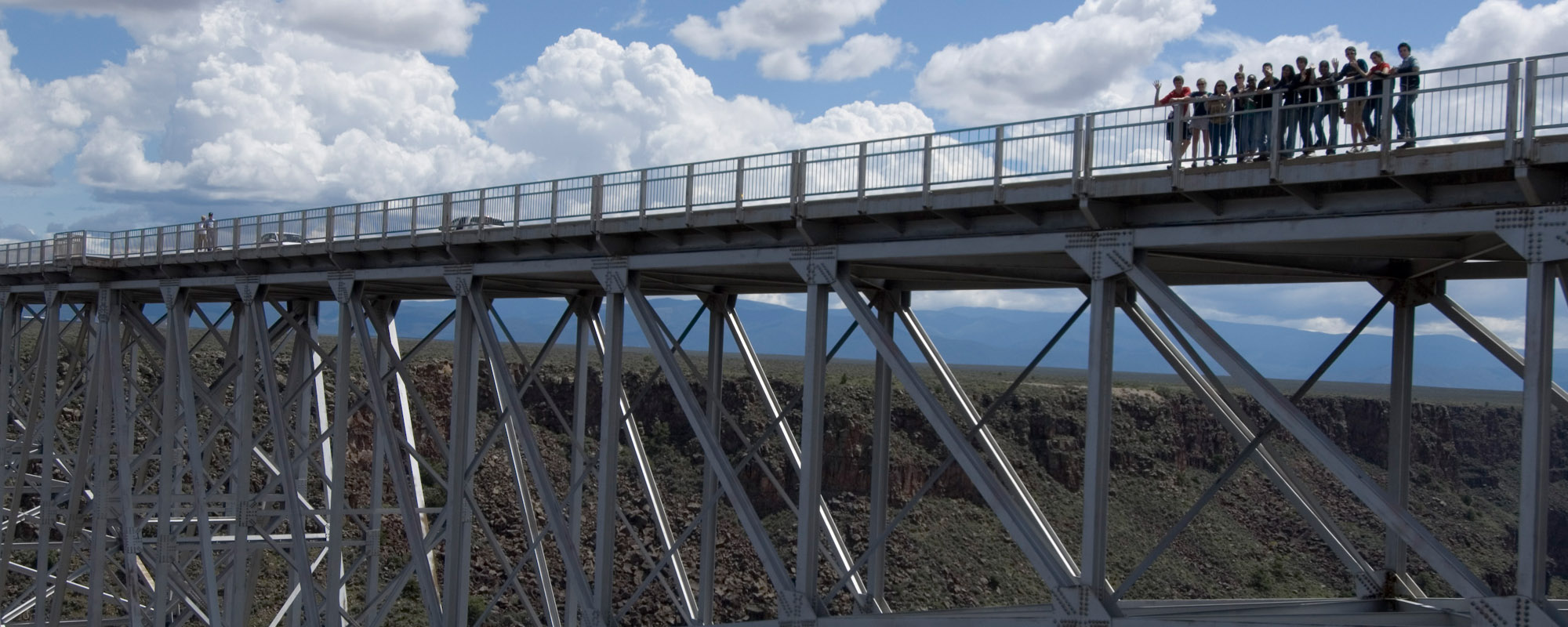  A group of students stands on a large steel bridge.