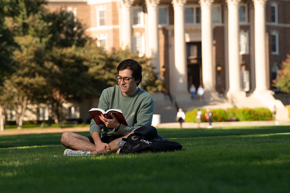 An SMU student reads on the Dallas Hall lawn